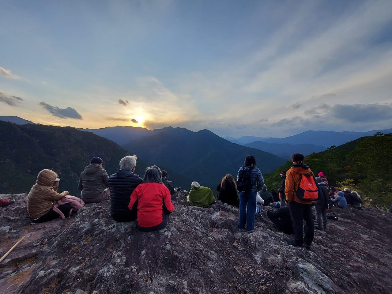 Pilgrims look out from a mountain ridge at dusk.